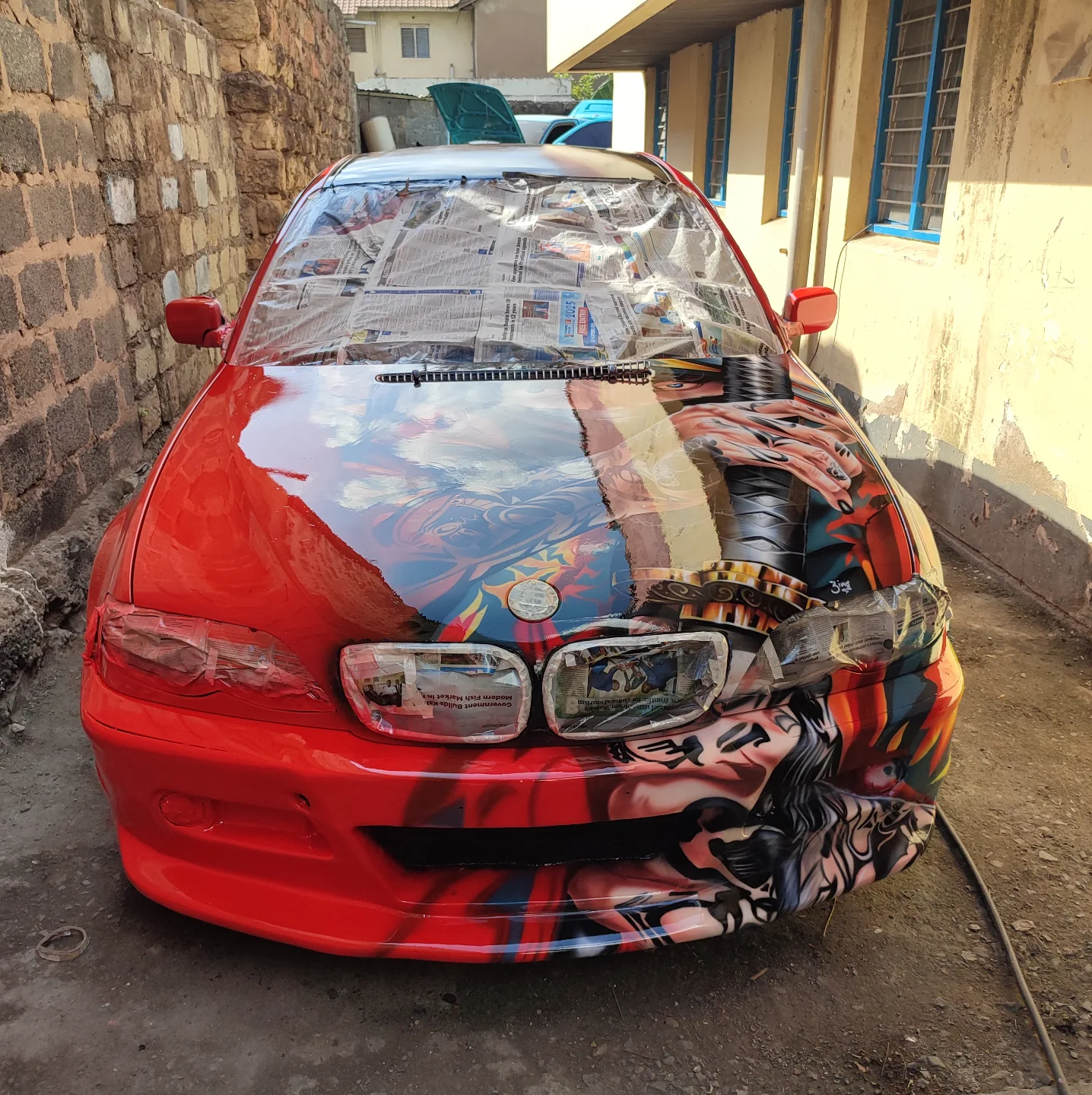 Red BMW with custom airbrush, masked up mid-job at Setik